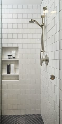 a white tiled shower with shelves on the wall