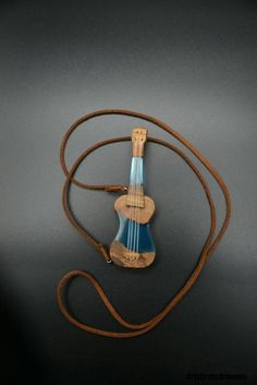 a small blue and white guitar on a brown cord with a wooden holder in the shape of an ukulele