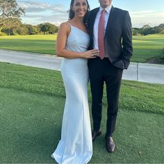 a man in a suit and tie standing next to a woman in a white dress