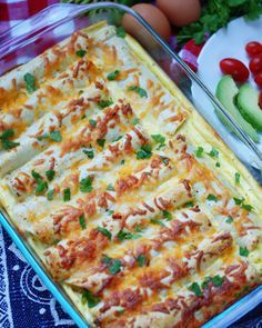 a casserole dish with cheese, tomatoes and cucumbers in the background