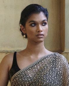 a woman in a black and gold sari is looking at the camera with an intense look on her face