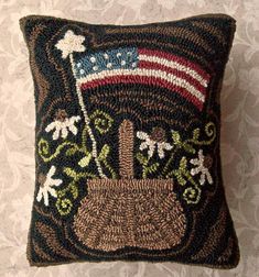 a decorative pillow with an american flag on it's back and flowers in the center