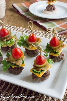 mini burgers with tomatoes, lettuce and cheese on a white platter