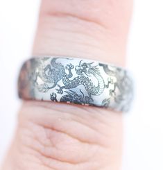 a person's hand with a ring on it that has an image of a dragon