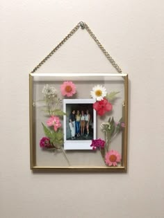 a gold frame with flowers hanging on the wall next to a white and pink wall