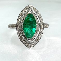 an emerald and diamond ring on a white surface