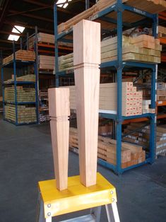 a wooden sculpture sitting on top of a yellow stool in a warehouse filled with boxes