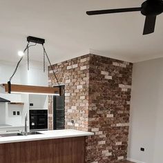 an empty kitchen with a brick wall and ceiling fan hanging from the ceiling above it