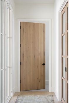 an empty hallway with a wooden door and rug on the floor in front of it