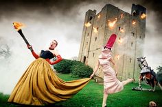 two women dressed in costumes and holding torches are running through the grass near a castle