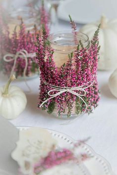 small jars filled with flowers and candles on top of a table