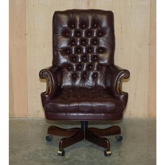 a brown leather office chair sitting on top of a wooden floor next to a wall