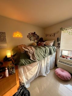 an unmade bed in a dorm room next to a window