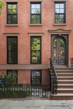 an apartment building with stairs leading up to the front door and two windows on each side