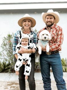 a man and woman standing next to each other holding a small white dog in their arms