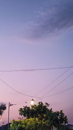 an intersection with traffic lights and power lines in the background at dusk, as seen from across the street