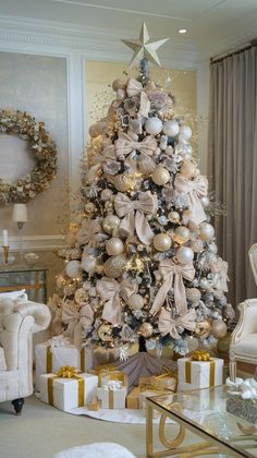 a decorated christmas tree in a living room with gold and silver ornaments on the top