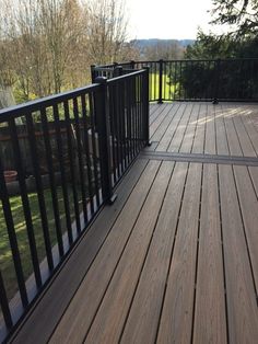 a wooden deck with black railings and trees in the background