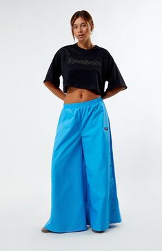 Stay effortlessly cool with these Reebok Angel Wide Leg Track Pants. Crafted from recycled fabric, they feature a low-rise, elastic waistband, side hand pockets, and snap-button details, all complemented by Reebok's soft-touch logo for a relaxed fit with wide-leg openings.13" rise28" inseam40" leg openingsSolid color track pantsLow-riseElastic waistbandSide hand pocketsSnap-button side detailsReebok soft-touch logoWide leg openingsRelaxed fit100% recycled polyesterMachine washableModel is wearing a size smallModel measurements: 5’9” height, 32” bust, 25” waist, 34” hipsMeasurements taken from a size smallLearn more about PacSun eco items Reebok Womens Angel Wide Leg Track Pants - Blue size Small Blue Workout Bottoms With Elastic Side Panels, Blue Athleisure Bottoms With Elastic Side Panels, Blue Wide Leg Sportswear Pants, Blue Sportswear Bottoms With Elastic Side Panels, Sportswear Wide Leg Blue Bottoms, Sports Wide Leg Bottoms With Elastic Side Panels, Sports Wide-leg Bottoms With Elastic Side Panels, Blue Wide Leg Sportswear Bottoms, Wide Leg Sports Bottoms With Elastic Side Panels