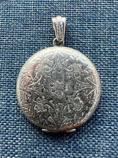 The center of this beautiful sterling silver sweetheart locket depicts a wild rose surrounded by decorative stems and flowers - such a pleasing and romantic design!  This locket is from the 1970's and is marked "BAB Sterling" on the interior of the locket.  The locket is round measures 1 1/4" in diameter.   The hinge is in working order with some visible scuffs to the finish. It is in very good vintage condition with some wear on the back, which is engraved "Love 1-24-72 L.G.E." The sterling silver bail is not original to the locket. Cowgirls and Saints gift box included. Silver Round Locket Necklace For Valentine's Day, Silver Locket Necklace For Valentine's Day, Victorian Hallmark Jewelry For Memorial, Victorian Silver Jewelry For Valentine's Day, Victorian Memorial Jewelry With Hallmark, Ornate Engraved Locket Necklace For Anniversary, Engraved Jewelry Collectible For Valentine's Day, Valentine's Day Vintage Etched Jewelry, Antique Round Jewelry With Hallmark