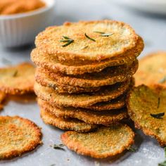 a stack of crackers sitting on top of a table next to a bowl of dipping sauce