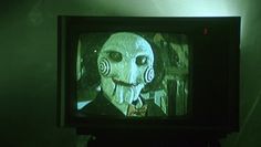 an old television with a creepy face on it's screen in a dark room