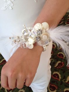 a close up of a person wearing a bracelet with pearls and feathers on it's wrist