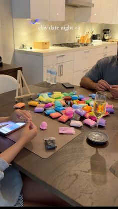 two people are sitting at a table with colorful marshmallows on it