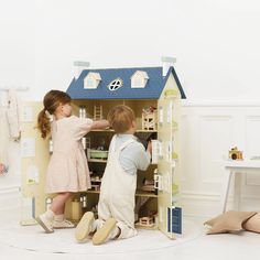 two children playing with a doll house in the living room