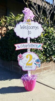 a welcome to charlotte's 2nd birthday sign on a potted plant in front of a house