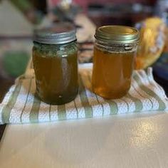 two jars filled with liquid sitting on top of a white towel next to each other