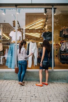 two women standing in front of a clothing store