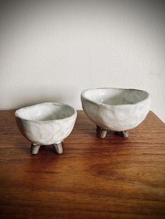 two white bowls sitting on top of a wooden table