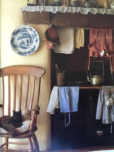 a cat laying on a chair in front of a shelf with pots and pans