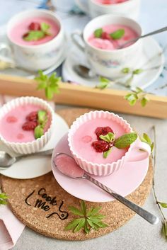 two desserts with raspberries in cups on a cork coaster