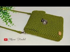 a green crocheted purse sitting on top of a white table next to a tree