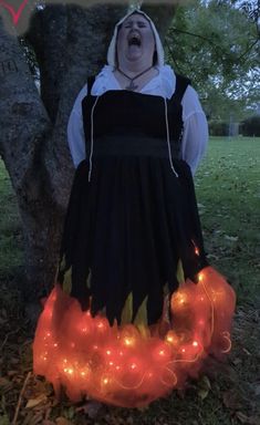 a woman in a costume standing next to a tree