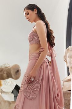 Blush pink pre-draped, lehenga saree with scallop detailing and highlighted with pearls, crystal embroidery. Paired with a padded blouse with all over sequins, thread, pearls and crystal work.
Components: 2
Pattern: Embroidery, Embellished
Type Of Work: Scallop, Thread, Beads, Sequins, Pearl, Crystal
Neckline: Scoop Neck
Sleeve Type: Sleeveless
Fabric: Flat Chiffon and Organza
Color: Pink
Other Details: 
Model height: 5 ft 7 inches, wearing size XS
Blouse:
Padded

Occasion: Destination Wedding - Bollywood Style Side Open Wedding Set, Draped Sharara With Mirror Work For Diwali, Diwali Sharara With Mirror Work And Draped Style, Traditional Side Open Choli For Wedding, Traditional Wedding Choli With Side Open, Bollywood Style Side Open Wedding Dress, Bollywood Style Wedding Dress With Side Open, Side Open Lehenga With Unstitched Blouse For Reception, Semi-stitched Wedding Saree