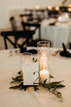 A romantic grouping of hurricane candles on top of  sprigs of greenery is a perfect touch to this elegant and modern wedding reception.

- Olivia Doerfler Photography Modern Simple Wedding Centerpieces, Minimal Candle Wedding Decor, Very Simple Wedding Centerpieces, Simplistic Table Decor Wedding, Wedding Table Decorations Simple Elegant, Simple Wedding Table Decor Candles, 3 Candle Centerpiece, Candle Center Piece For Wedding Tables, Simple Greenery Wedding Decor