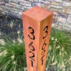 a wooden block with numbers on it sitting in front of a brick wall and grass