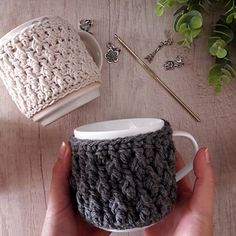 a person holding a coffee cup in their left hand and crocheted mug cozy