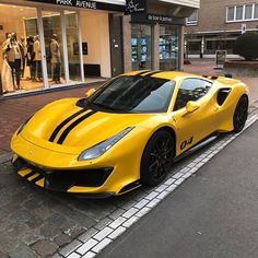 a yellow sports car is parked on the side of the road in front of a store