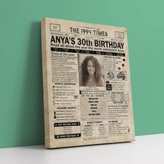 an old newspaper with a woman's 30th birthday photo on it, sitting against a green wall