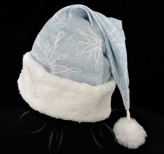 "Santa hat is made up in a soft powder blue flannel fabric with a white snowflake design. The hat accented with a snowy white soft Sherpa faux fur fabric turn up brim. Proportions of the hat are generous and will fit most head sizes, ladies or gents. The styling is a slouch cone, relaxed fit, traditional Santa style hat. Measurement for opening for your head is 24-25\" circumference and the length is 19\". There is a snowy white faux fur pompom dangle." Cheap Blue Winter Hats, Adjustable Blue Mini Winter Hats, Blue Santa Hat, Adjustable Light Blue Winter Hat, Cozy Blue Winter Hat, Christmas Party Hat, Christmas Party Hats, Blue Flannel, Christmas Celebration