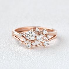 a rose gold ring with three diamonds on the top and bottom, sitting on a white surface