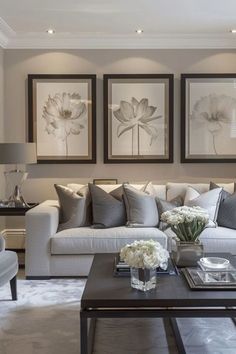 a living room filled with white furniture and pictures on the wall above it's coffee table