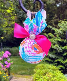 an ornament hanging from a metal hook with a pink bow on it's end