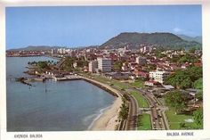 an aerial view of a city next to the ocean with mountains in the back ground