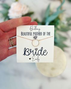 a hand holding a card that says beautiful mother of the bride with two rings on it