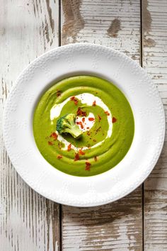 a white bowl filled with green soup on top of a wooden table